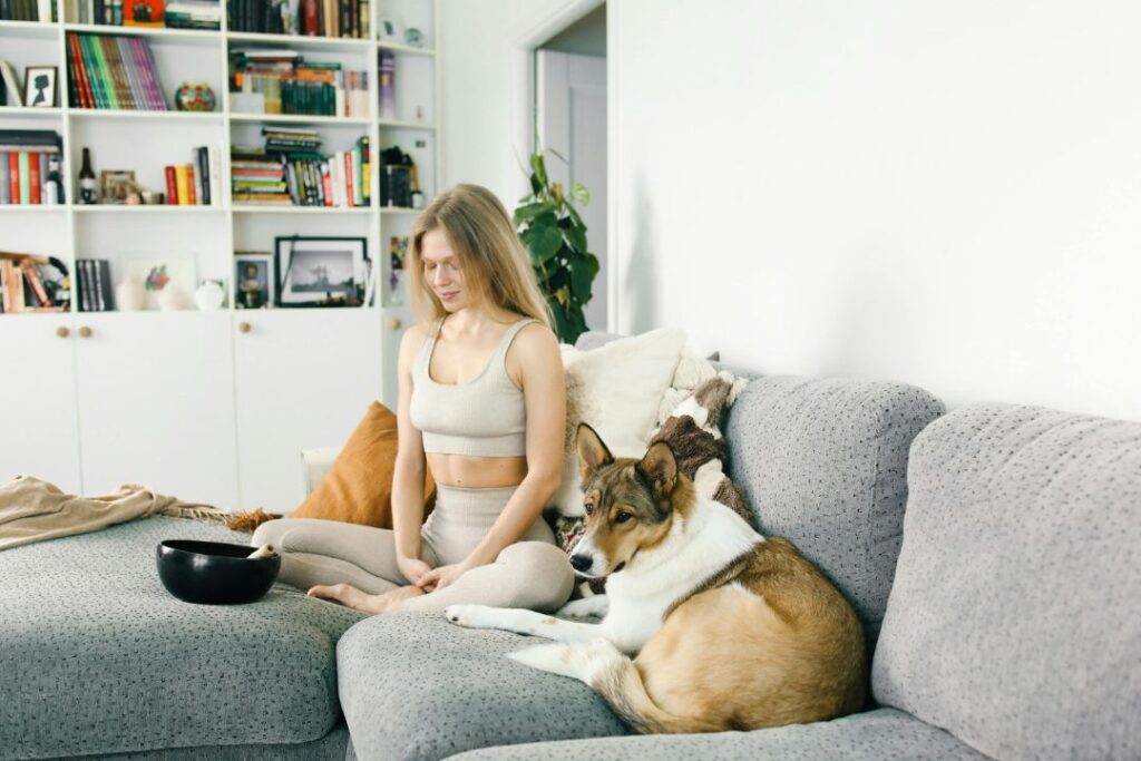 a woman sitting on a setee meditating with her dog