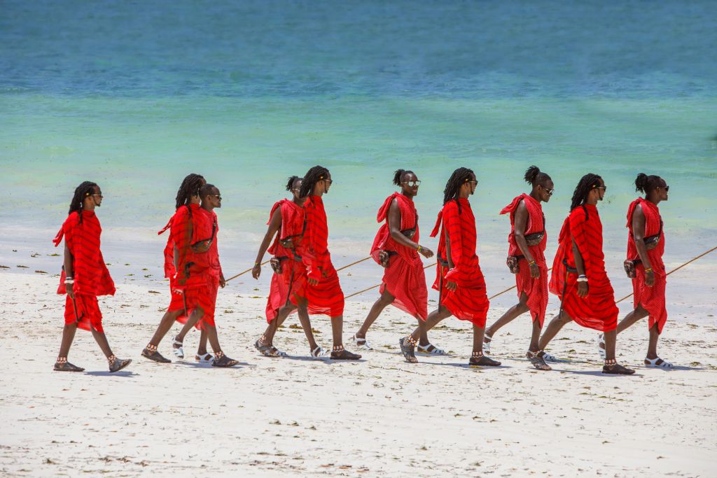 a group of women all dressed in red walking along the shoreline