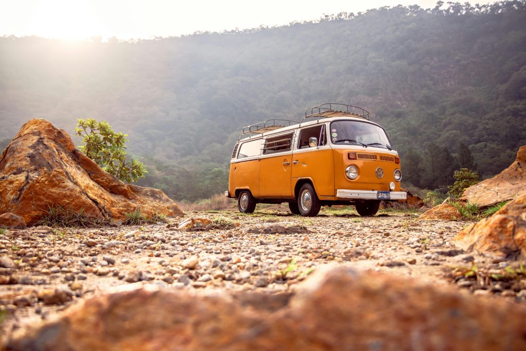 a yellow VW campervan in a remote landscape of rock and trees