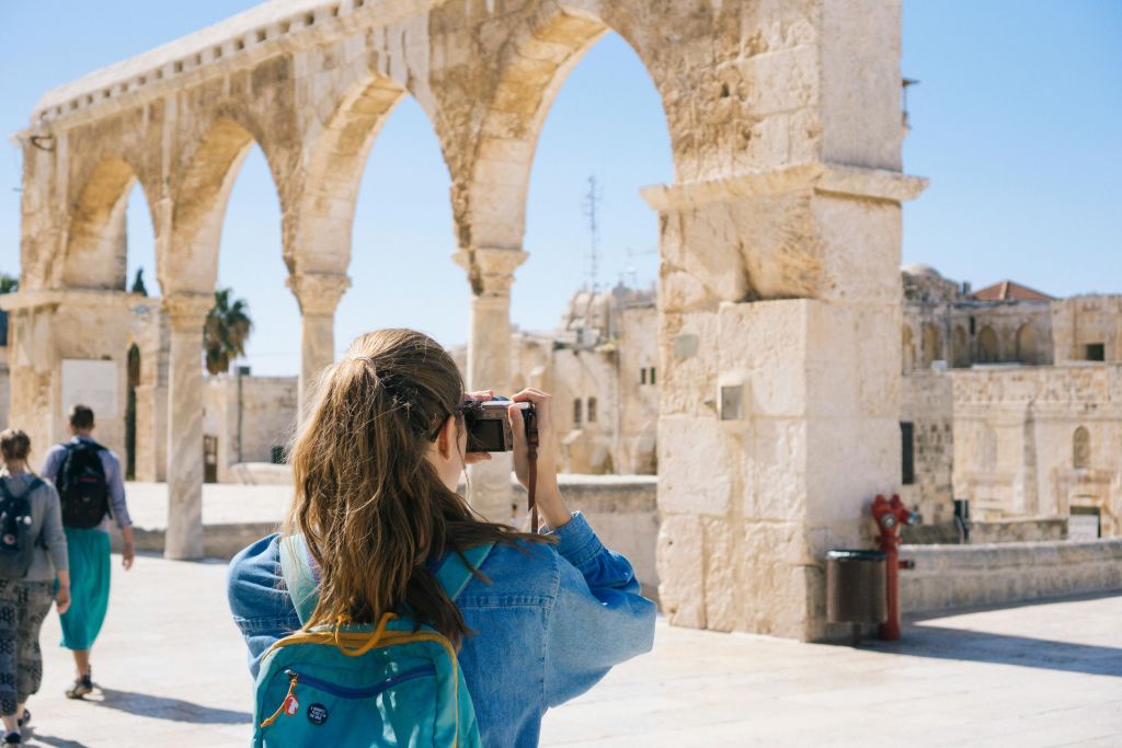 a woman taking a picture of some ancient ruins for some travel content