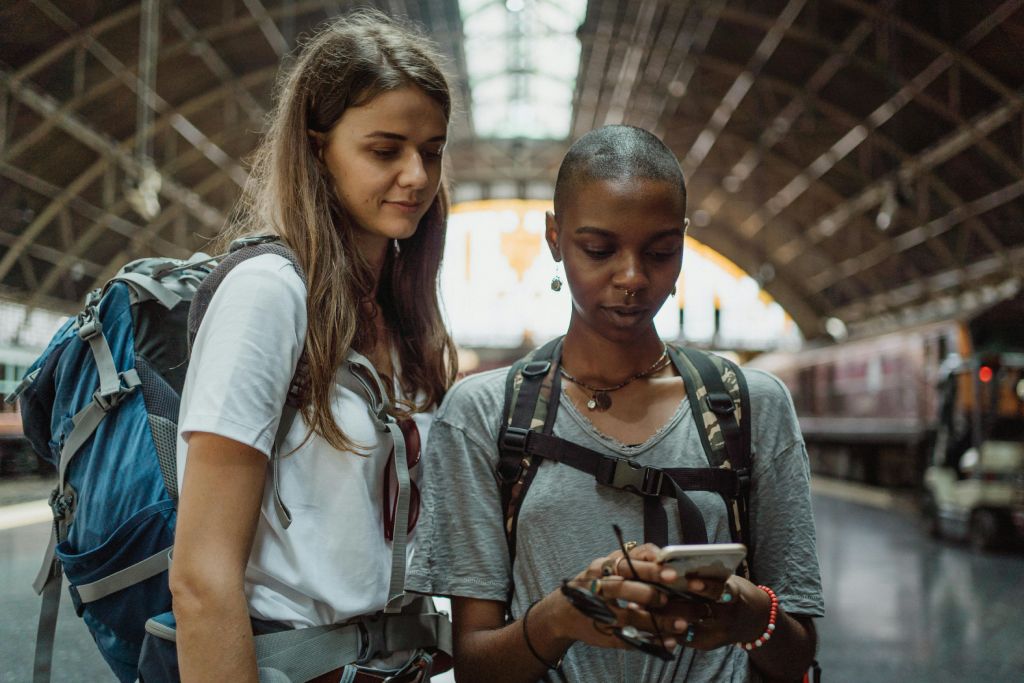 two young women using a travel app while travelling