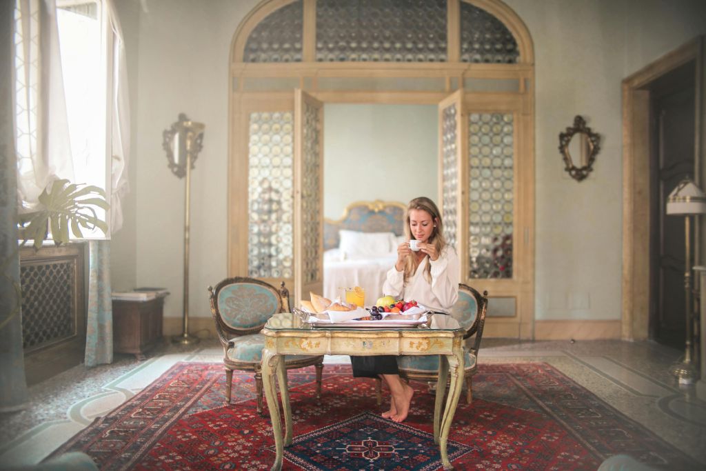 A woman sitting in a luxury hotel sipping tea.